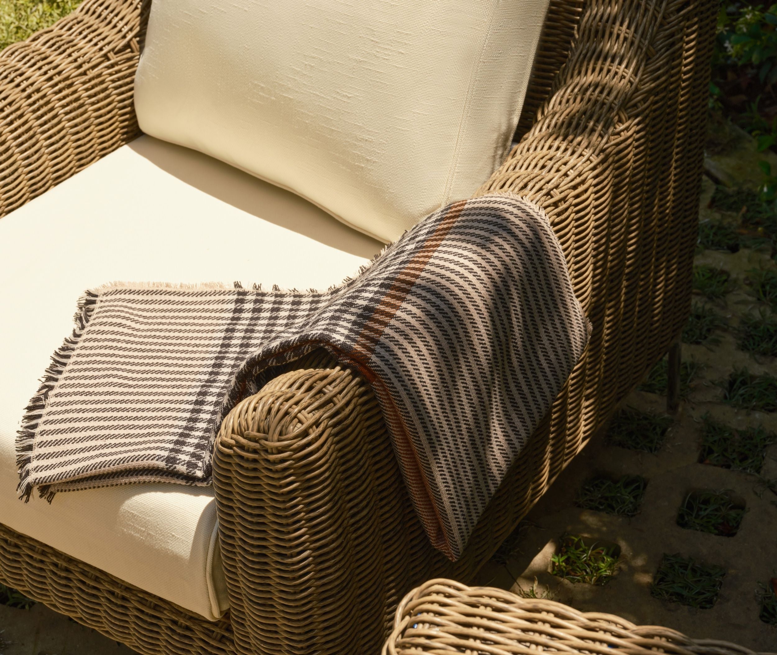 Woven outdoor armchair with cushion and throw blanket
